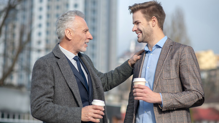 older man with hand on shoulder of young man