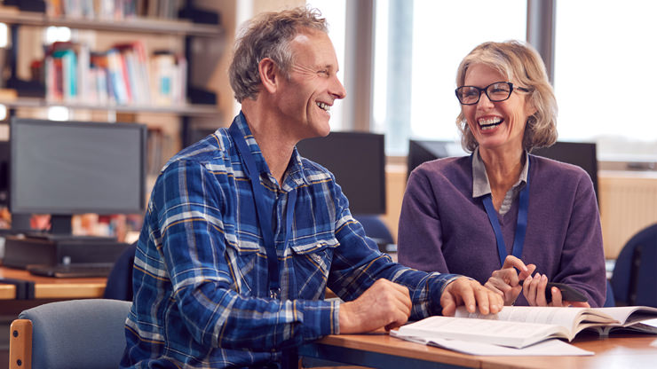 older man sitting at desk next to woman student